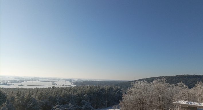 Schneebedeckte Landschaft unter klarem, blauem Himmel. Winterliche Stille und Weite.