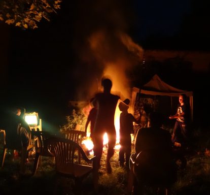 Menschen versammeln sich um ein Feuer im Garten bei Nacht.